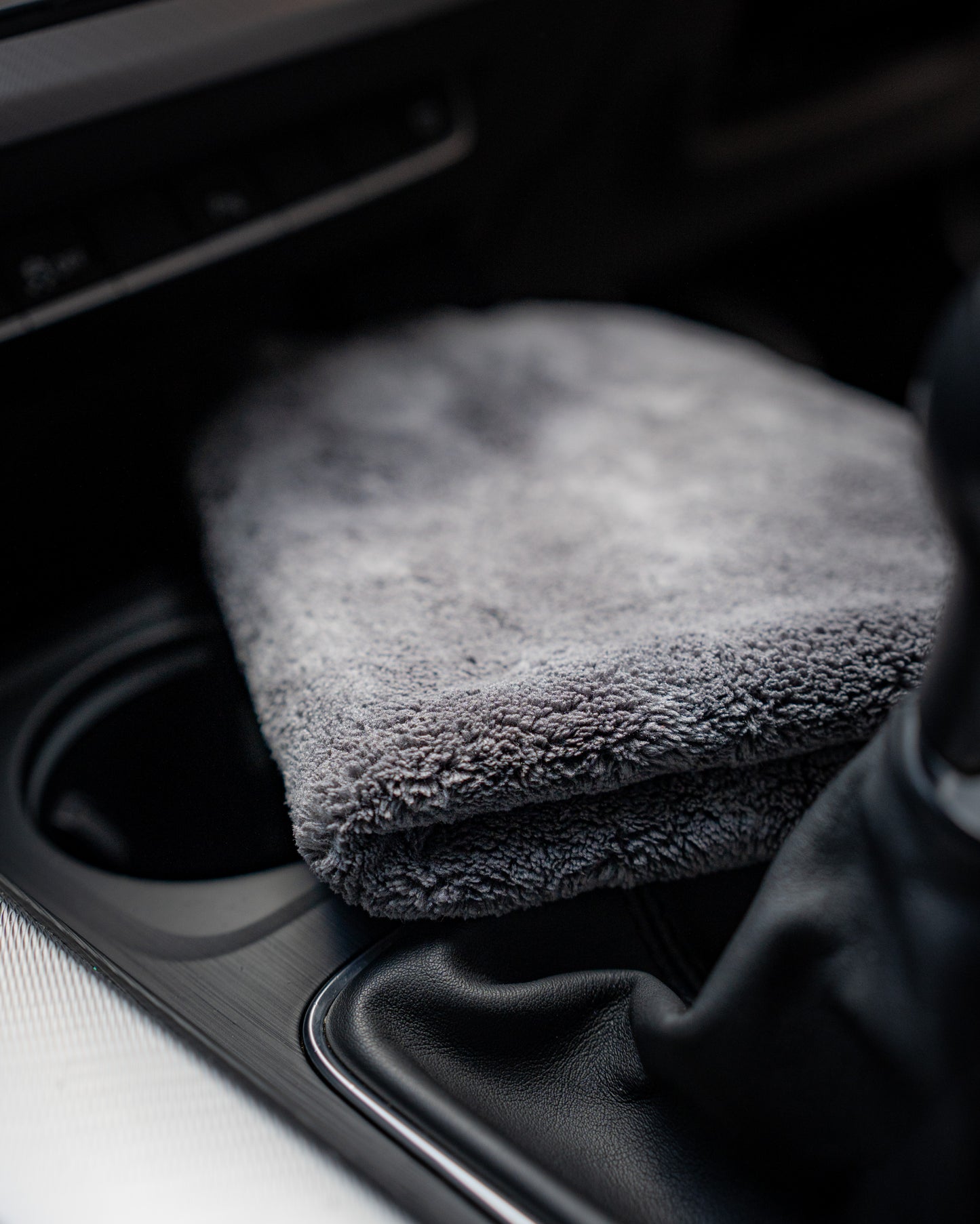 A folded FibreKing Ultimate Detailer Cloth is placed on the center console near the gear shift inside a car, ensuring your interior gets a lint-free finish.