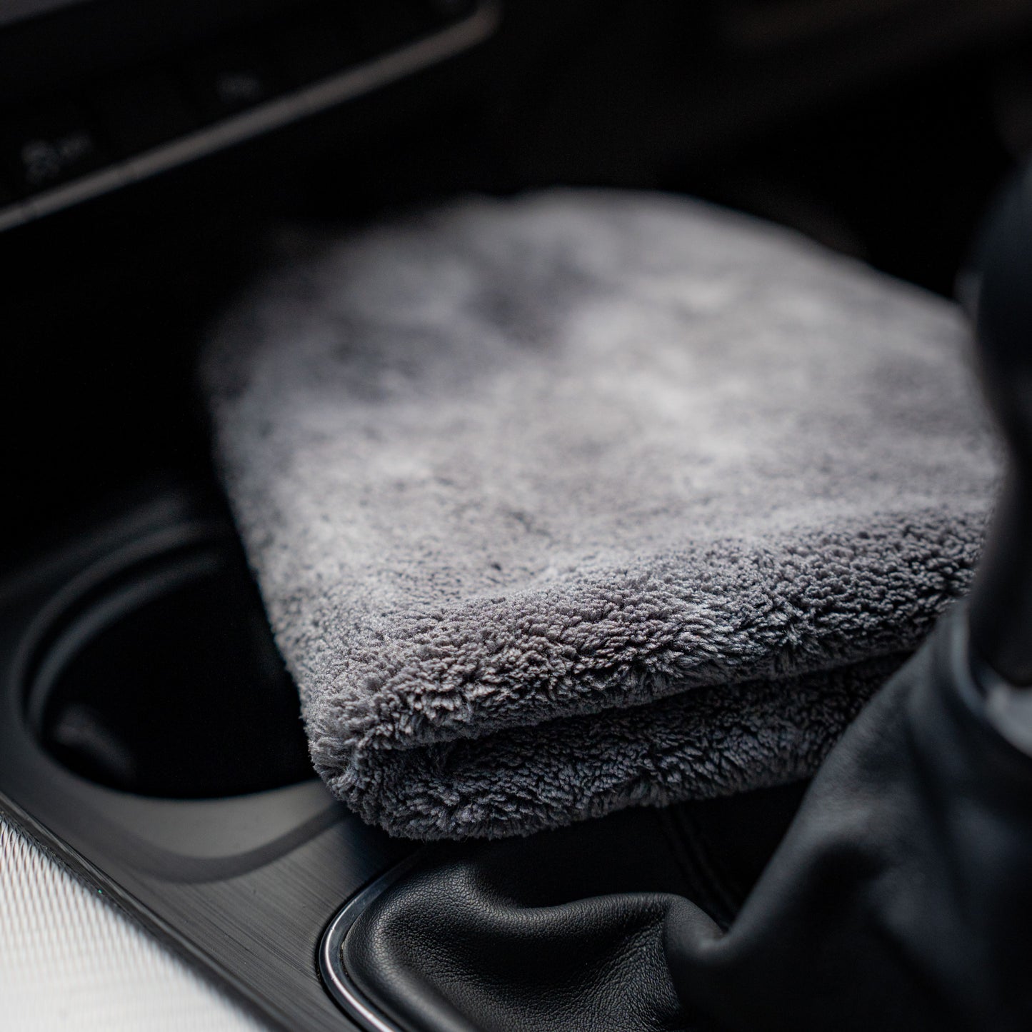 A folded FibreKing Ultimate Detailer Cloth is placed on the center console near the gear shift inside a car, ensuring your interior gets a lint-free finish.