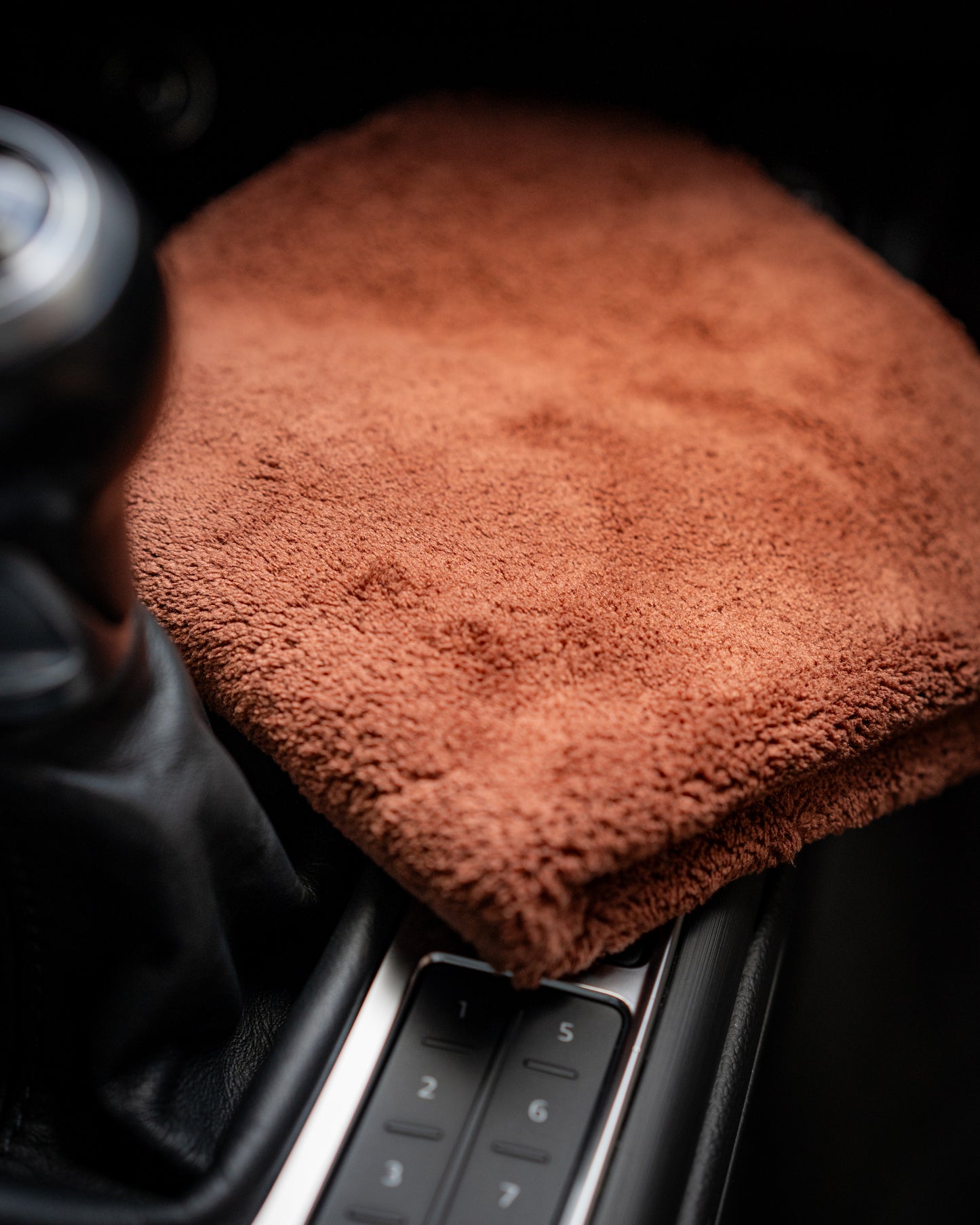 A brown FibreKing Ultimate Detailer Cloth sits on the center console by the gear shift, ready to deliver a lint-free finish.