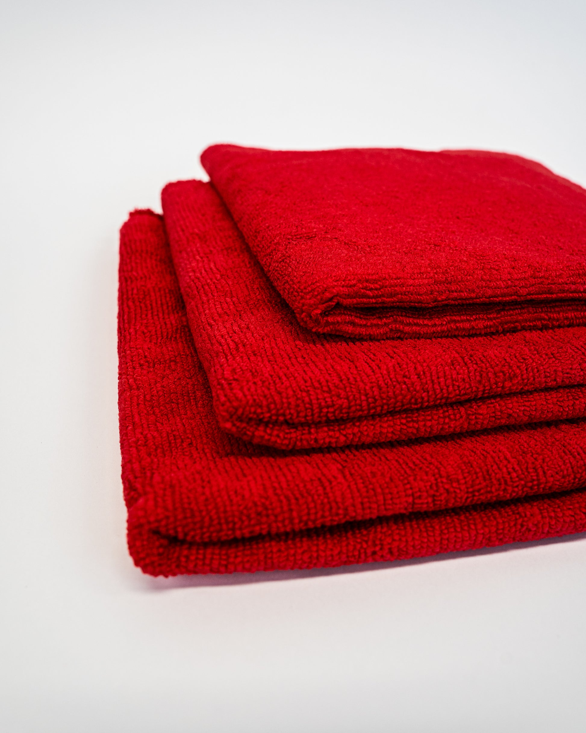 Three FibreKing Duplex edgeless cloths in red, stacked neatly, come in a 3 pack—perfect as premium microfibre detailing cloths for any cleaning task.