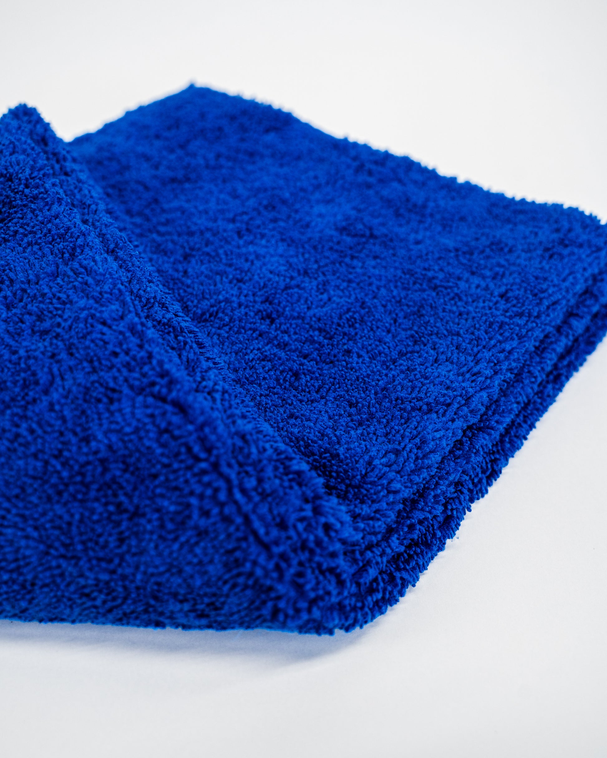 A close-up of a folded FibreKing Duplex edgeless cloth (3 pack) in bright blue dual pile microfiber, displayed on a plain white surface.