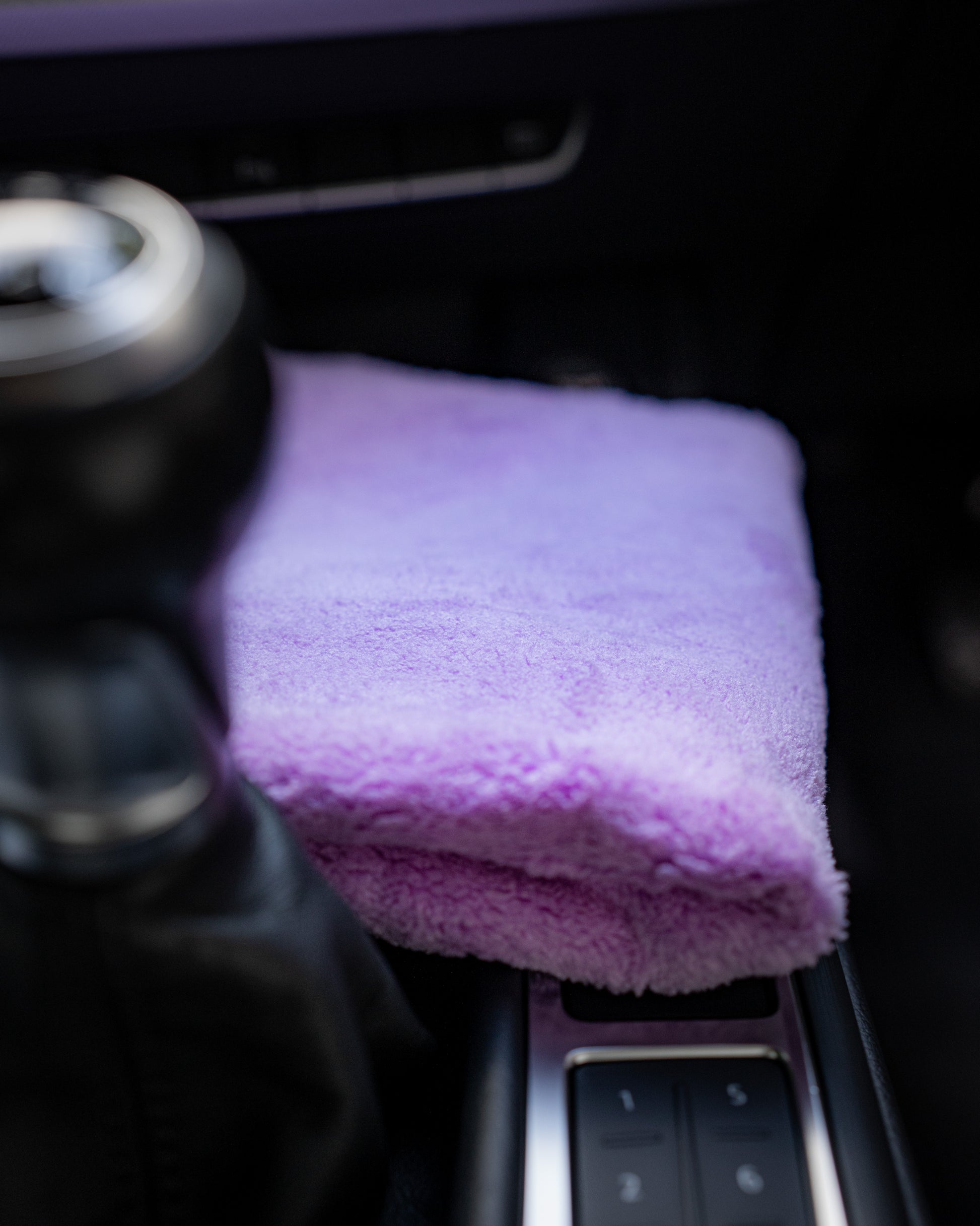 A FibreKing Ultimate detailer cloth, folded and lint-free in purple, sits on the car’s center console beside the gear shift.