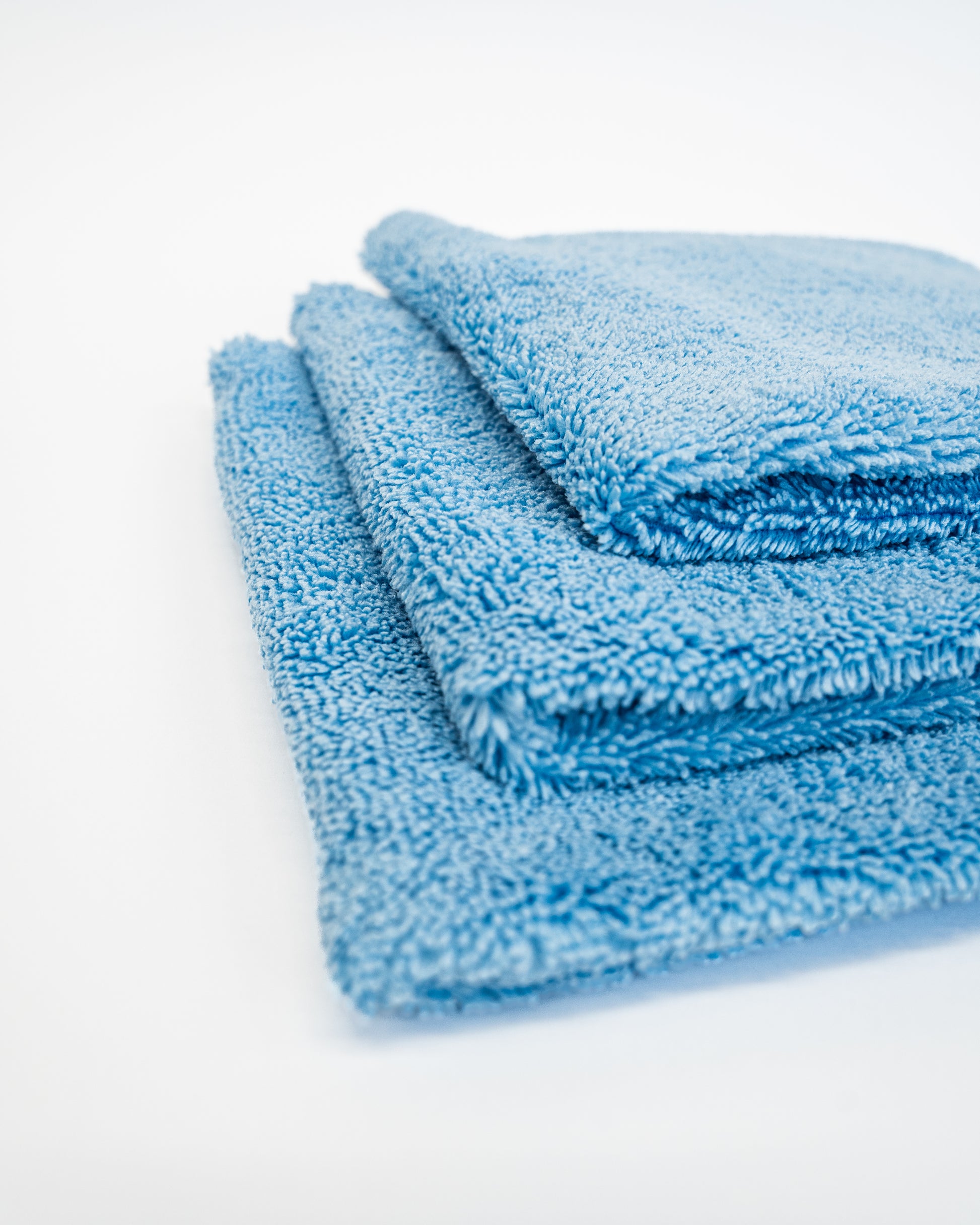Three FibreKing Duplex edgeless cloths in Baby Blue, featuring dual pile microfiber, are folded and stacked neatly on a white surface.
