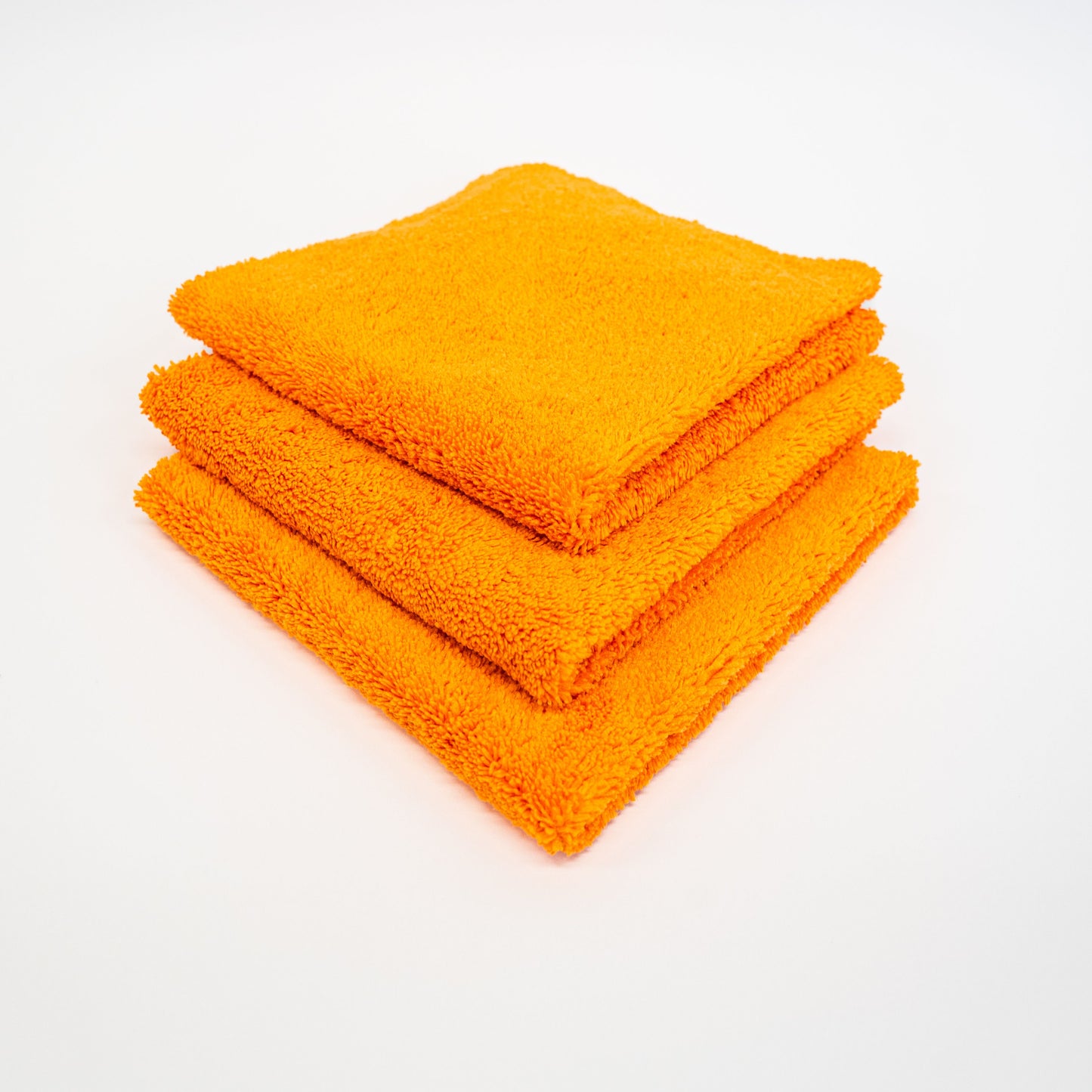 Three orange FibreKing Duplex edgeless cloths (3 pack) are neatly folded and stacked on a white surface.