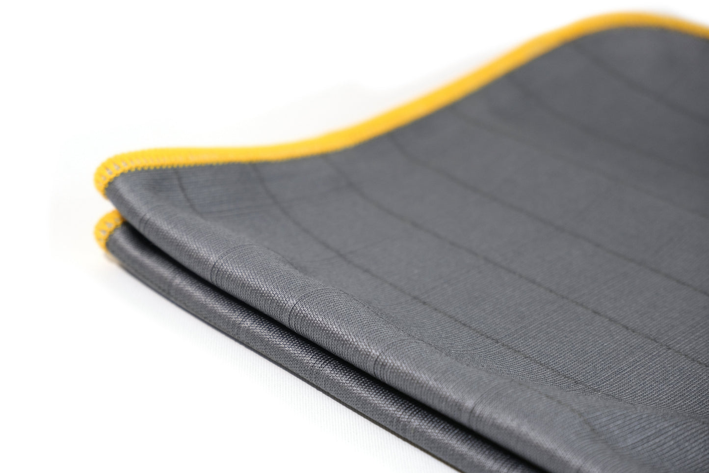 A close-up of a folded FibreKing Carbon Glass Cloth from the 3 Pack shows its gray anti-static microfiber with stitched grid lines and a yellow-edged border on a white background.