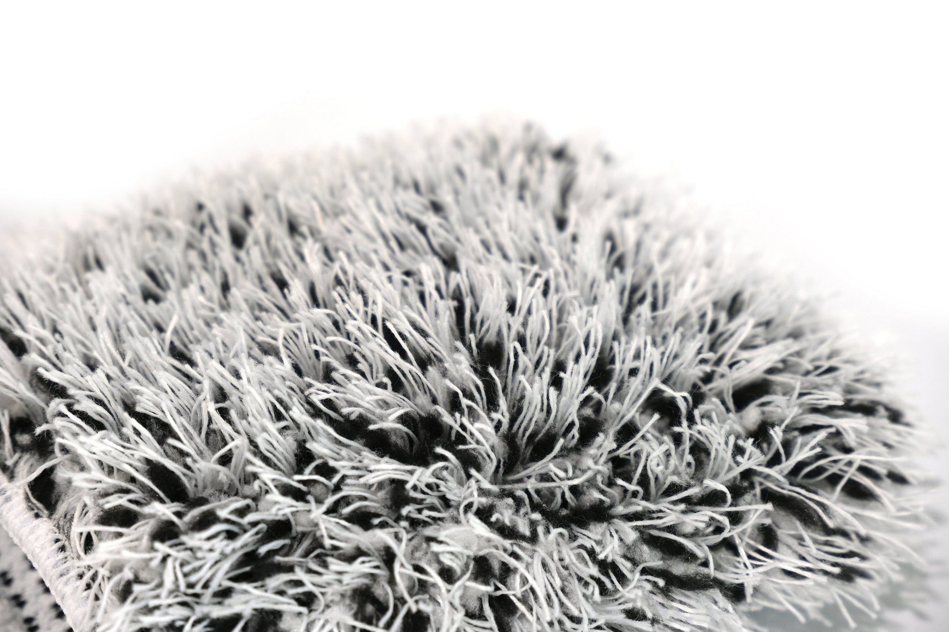 Close-up of the edge of FibreKing’s Gold Label Korean Wheel Mitt in gray and white, highlighting the thick, shaggy microfiber fibers on a plain white background and showcasing precision-crafted detailing.