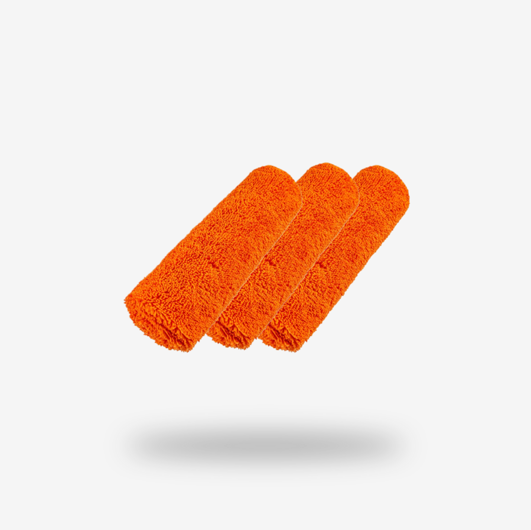 Three FibreKing Duplex edgeless cloths (3 pack) in orange are rolled and arranged side by side on a white background, with a soft shadow beneath them.