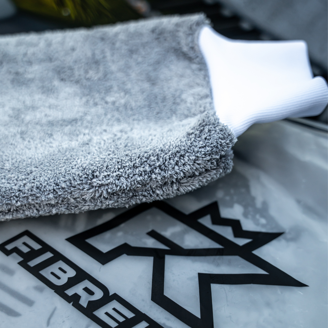 A close-up of the FibreKing PS Korean Microfibre Mitt in grey with a white cuff, featuring the black FIBRE logo, designed for scratch prevention.