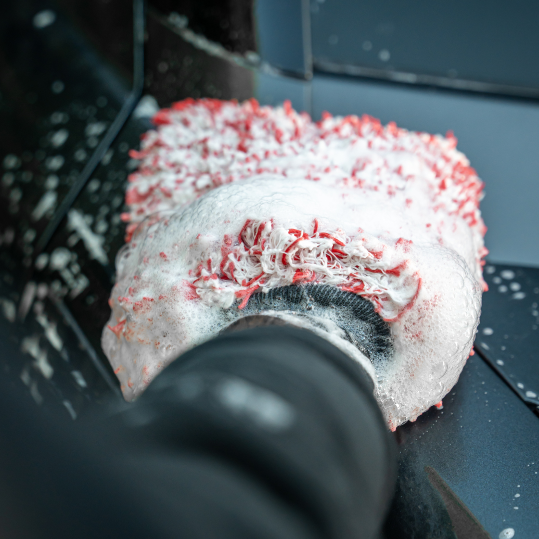 A person cleans a black car using the FibreKing SK Korean Microfibre Premium Wash Mitt -Red, a foamy wash mitt with red and white fibres from FibreKing.