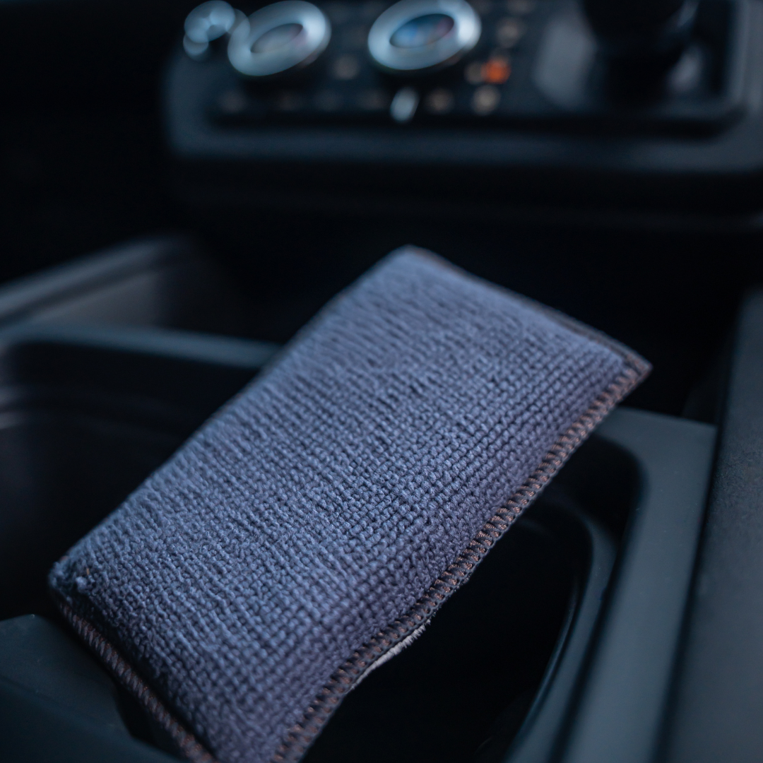 Two gray FibreKing Scrub Pads from the 2 pack rest in a car cup holder, with the dashboard and control dials visible in the background.