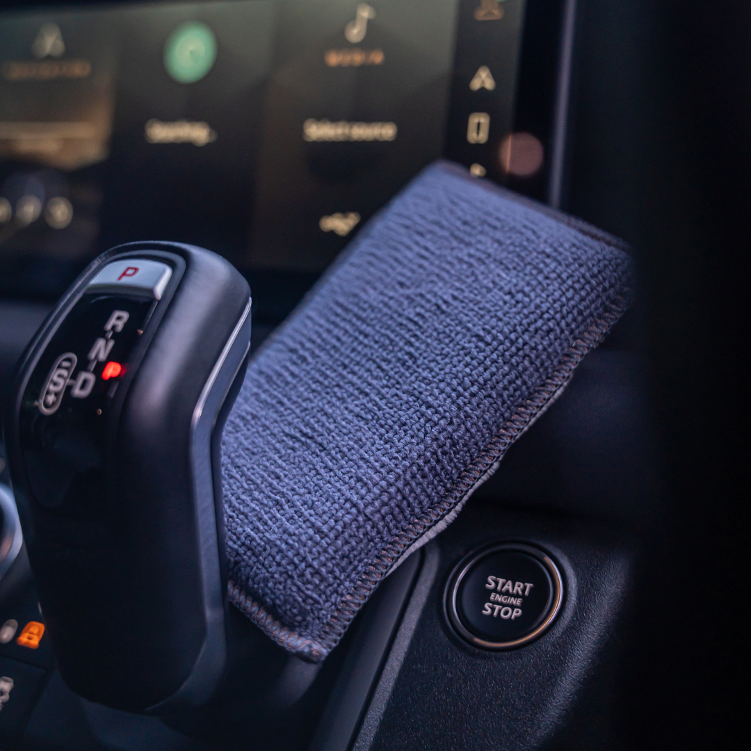 Close-up of a car gear shift lever with a FibreKing Scrub Pads 2 pack cleaning pad draped over it, showing its multi-surface compatibility near an illuminated start/stop button and a digital display.