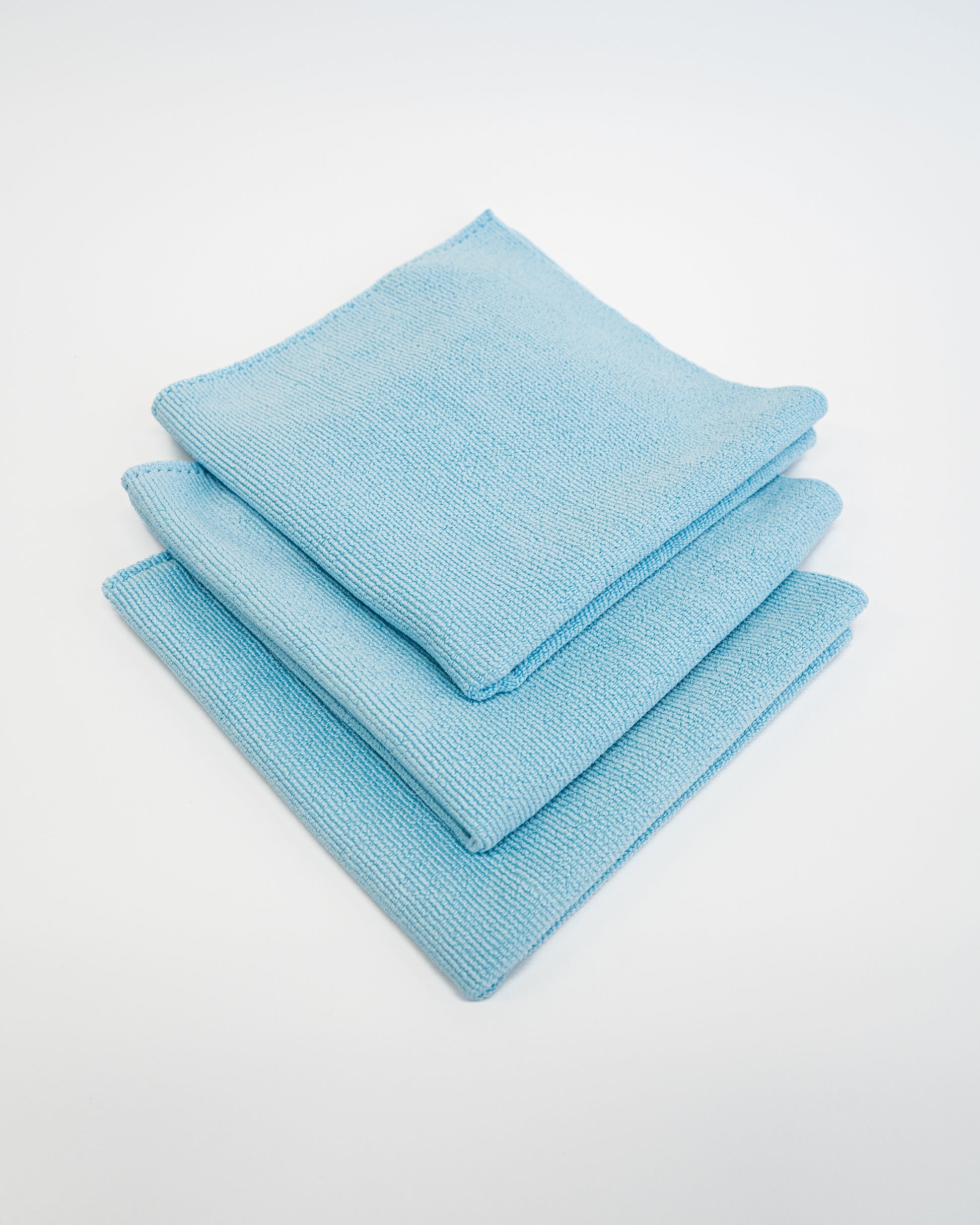 Three neatly stacked FibreKing Soft Edgeless Multi-Purpose Microfibre Cloths in light blue, perfect for detailing, are displayed on a plain white background.