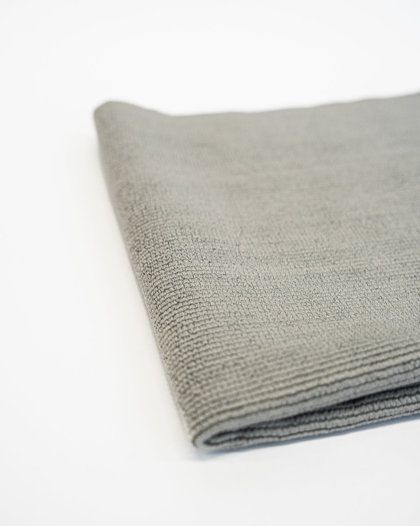 A folded FibreKing Soft Edgeless Multi-Purpose Microfibre Cloth in gray rests on a white surface.