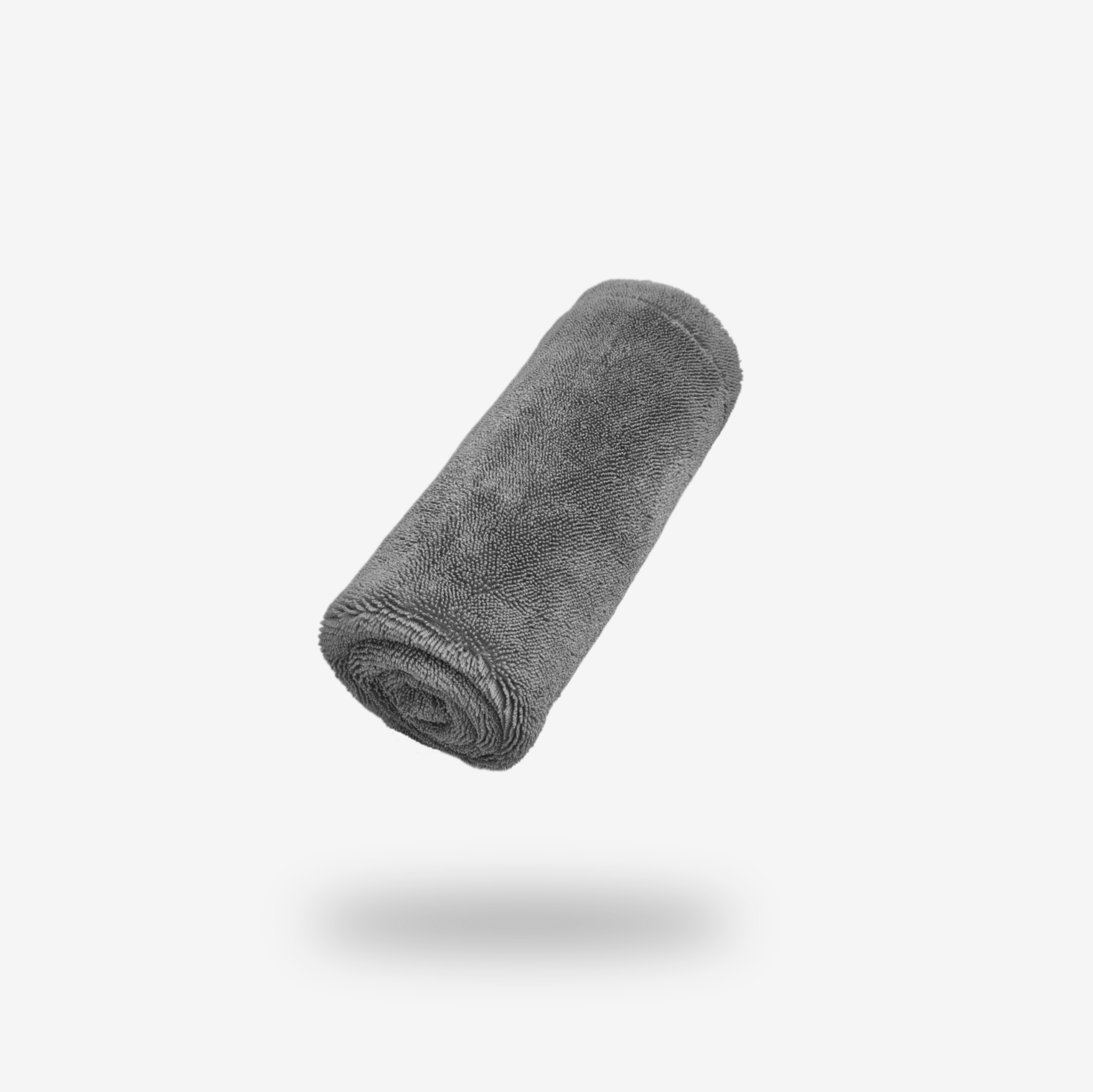 A rolled-up FibreKing Silver Label Drying Towel floats above a white surface, casting a soft shadow below.
