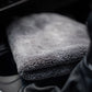 A folded FibreKing Ultimate Detailer Cloth in soft grey rests on a car’s center console near the gear shift and cup holders.