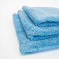 Three FibreKing Duplex edgeless cloths in Baby Blue, featuring dual pile microfiber, are folded and stacked neatly on a white surface.