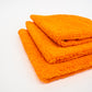 Three orange FibreKing Duplex edgeless cloths (3 pack), ideal as dual pile microfiber detailing cloths, are neatly stacked on a white surface.