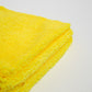 A close-up of a folded yellow Duplex Edgeless Cloth from FibreKing, shown on a white surface—this dual pile microfiber towel comes in a 3 pack and is perfect as a detailing cloth for spotless cleaning.