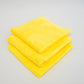 Three neatly folded yellow Duplex edgeless cloths by FibreKing, stacked on a white surface. This 3-pack of microfiber towels is perfect for spotless cleaning and detailing.