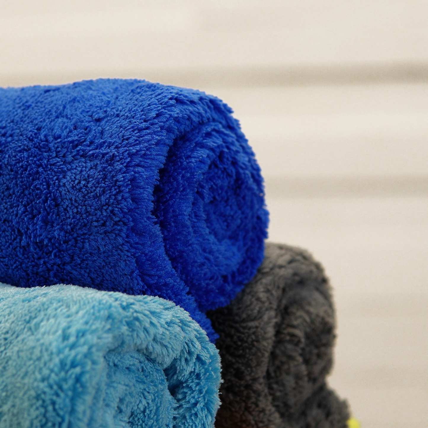 Three Ultimate Detailer Cloths by FibreKing in blue, light blue, and dark gray coral fleece microfiber are stacked together. Ideal edgeless cloths for car care or gentle home cleaning.