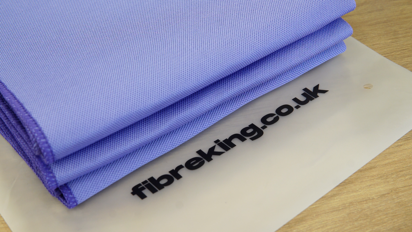 A folded Gold Label Korean Glass Cloth from FibreKing lies on a translucent mat with fibreking.co.uk printed in black, offering streak-free cleaning and high absorption. Pack contains 3 premium microfibre cloths.