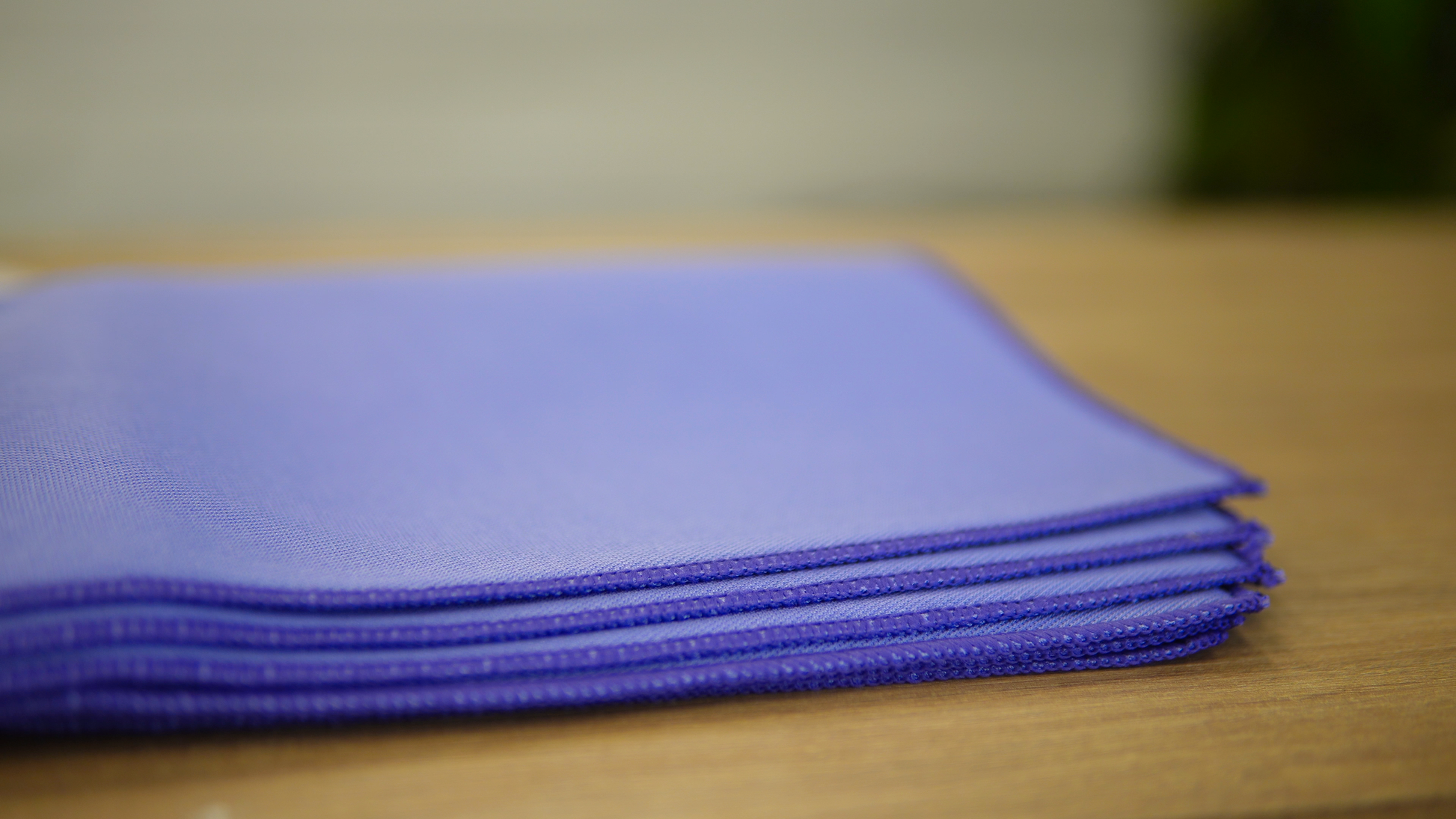 A close-up of FibreKing Gold Label Korean Glass Cloths (3 Pack) stacked on wood, ideal for streak-free cleaning and high absorption.