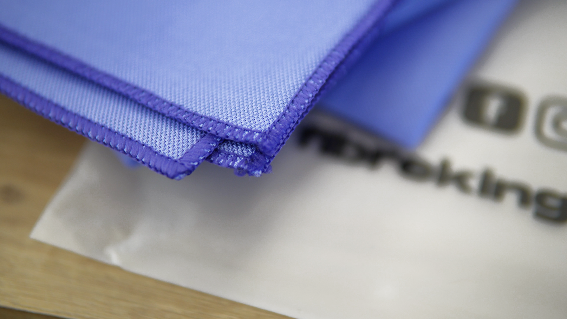 A close-up of FibreKing Gold Label Korean Glass Cloths (3 Pack) stacked on a printed sheet, showcasing their blue microfibre material known for high absorption and streak-free cleaning.