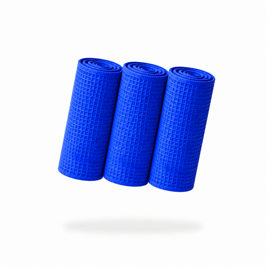Three rolled FibreKing Waffle Weave Towels - 3 Pack are arranged vertically against a white background, their textured blue fabric casting a shadow below.