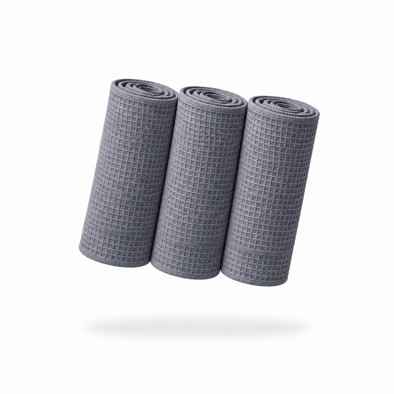 Three FibreKing Waffle Weave Towels - 3 Pack are rolled up side by side on a white background, each towel in soft gray with a faint shadow beneath.