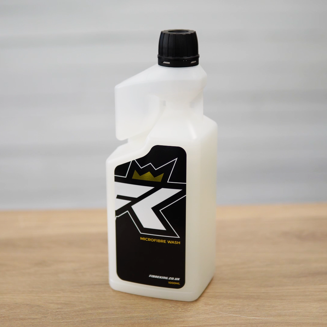 A white plastic bottle with a black cap and label featuring FibreKing’s stylized K and crown design, placed on wood—a perfect fit for your Microfibre Wash towel cleaner or microfibre care routine.