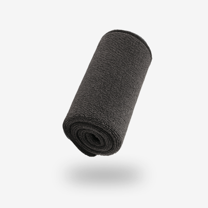 A FibreKing Premium Drying Towel, featuring twist loop technology and a dark gray color, is rolled up and centered on a white background with a soft shadow beneath it.