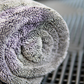 A close-up of a rolled Silver Label Drying Towel by FibreKing on a dark, textured surface emphasizes its premium quality for car detailing.