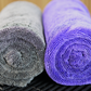 Two rolled FibreKing Silver Label Drying Towels, one gray and one purple, are placed side by side on a black textured surface.